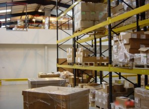 Adjustable pallet racking with mezzanine and gate in background